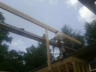 Carpenter setting a ridge beam over a new addition frame — Ice Dam Removal by Roofing Brothers in Lempster