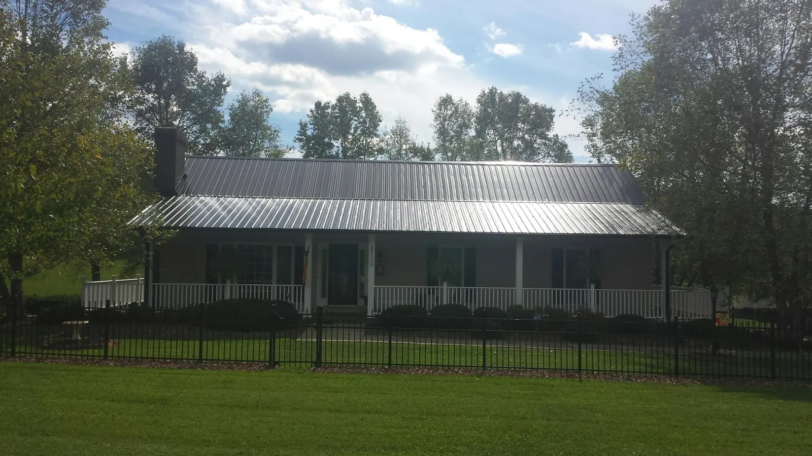 Gray metal roof on a brick ranch with a full width front porch — Gutter Guard Installation work by our crew in Lempster