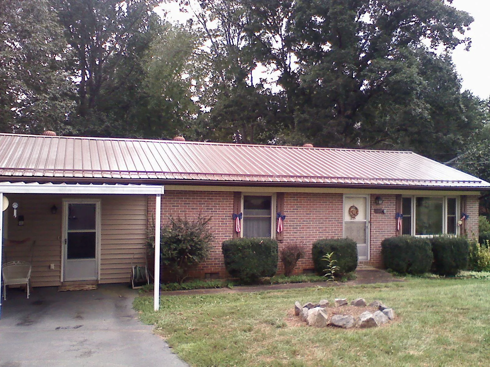 Bronze metal roof and carport on a brick ranch home — Roof Repair work by our crew in Lempster