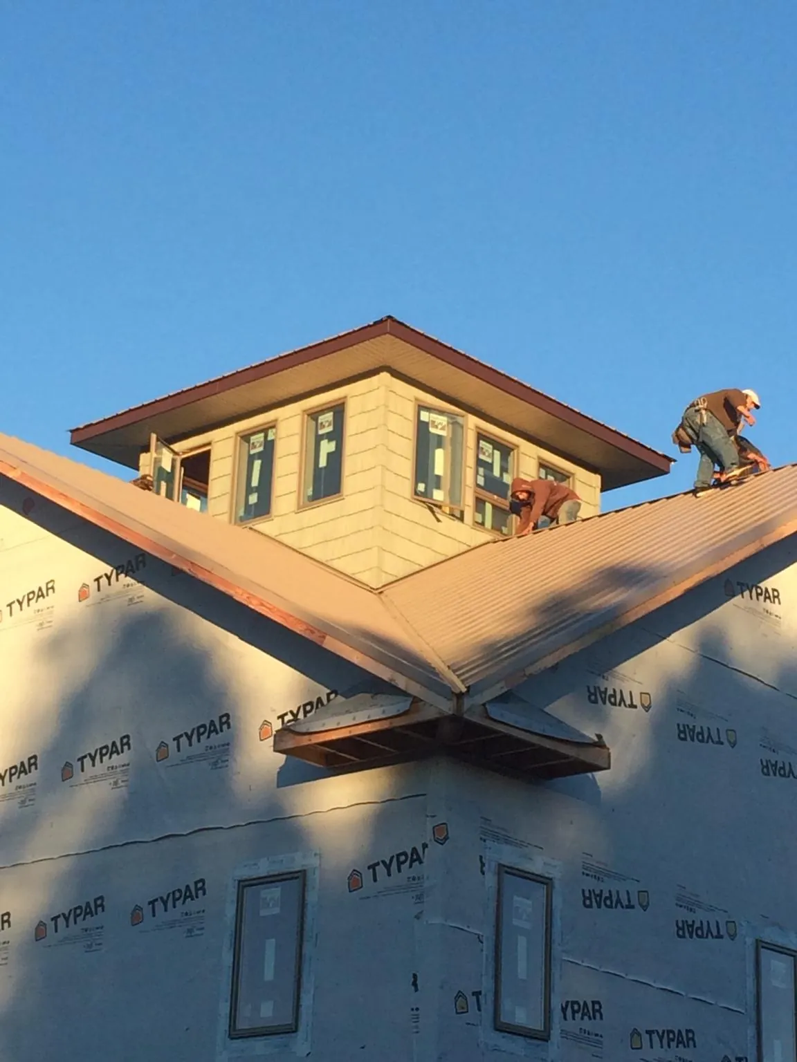 Roofers working around a rooftop cupola on a new metal roof at sunset — Roof Waterproofing in Lempster by Roofing Brothers